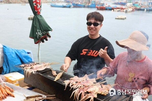 Korean travel Vlogger Kim JunBum (left) is trying the seafood barbecue  Photo by Wang Wen
