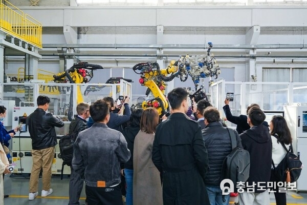 Observers watch industrial robots working based on instructions wirelessly transmitted at high speeds via 5G-Advanced indoor base stations